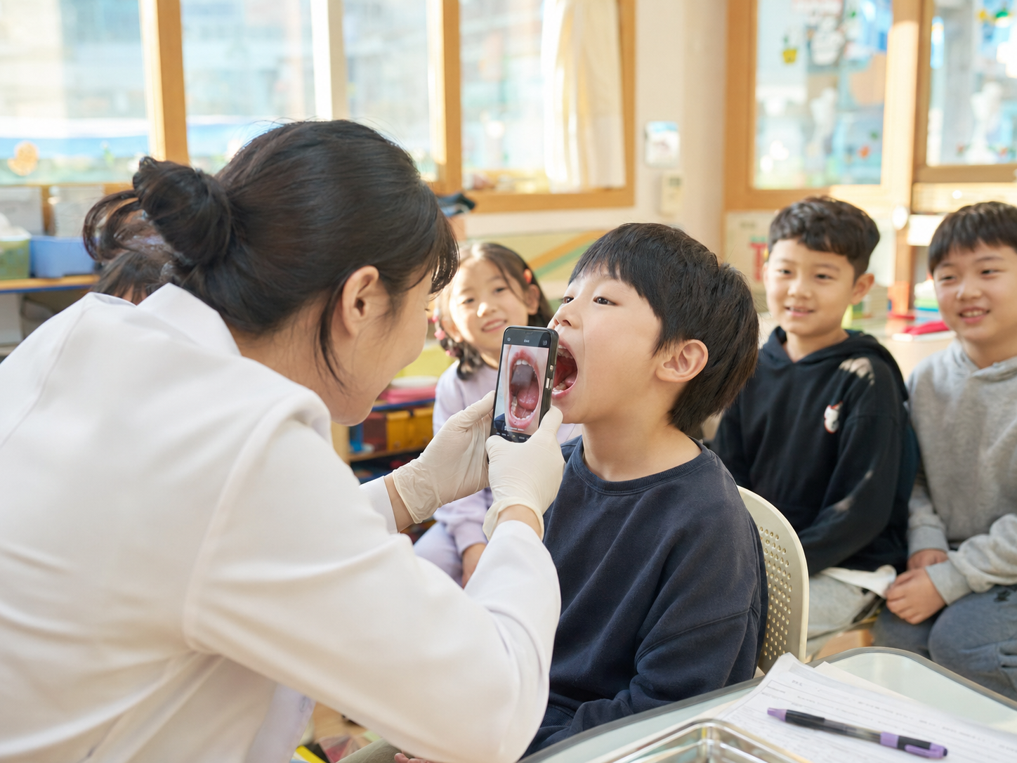 교실에서 스마트폰으로 학생의 구강을 촬영하는 공공 구강검사 현장